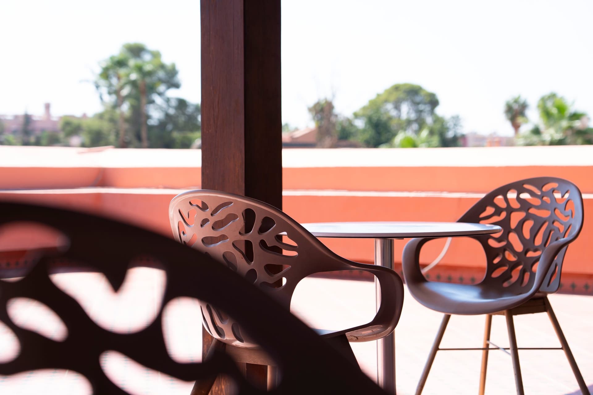 Une chaise ajourée sur la terrasse, des palmiers au loin